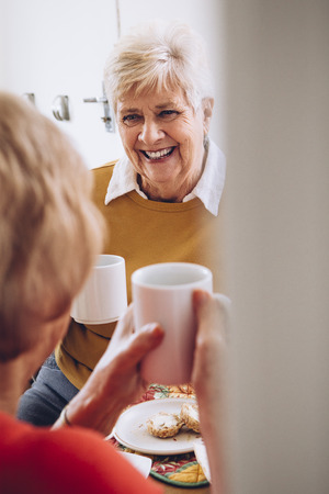 Senior women enjoying tea and cake in their care home.の写真素材