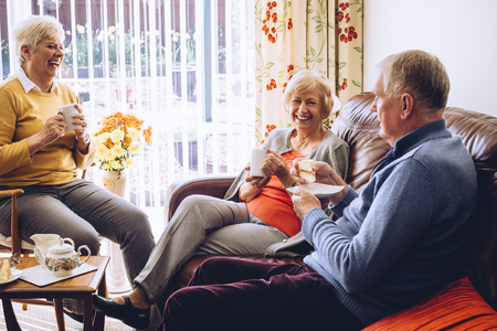 Three seniors enjoying tea and cake in the care home together.の写真素材