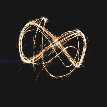 infinite shape made with a sparkler in a garden, using long exposure. の写真素材
