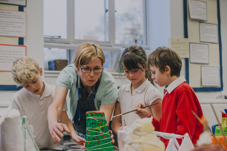 Primary school students are working with their teacher on a science project in the classroom. They...