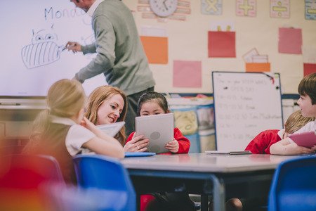 Group of students in a primary school are having a digital tablet lesson with their teacher.の写真素材