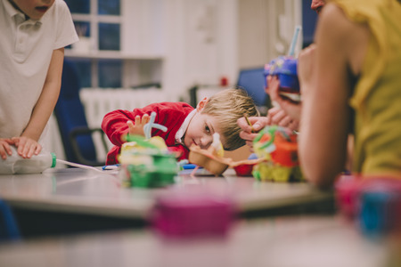 Little boy is measuring something he is building for a STEM project in school. He has used recycled objects and crafts equipment.の写真素材