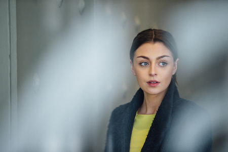 Businesswoman is standing in her workplace, looking out of her office window.の写真素材