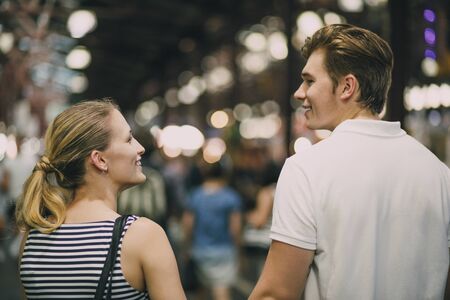 Happy couple are talking as they walk together through Queen Victoria Market, Australia.の写真素材