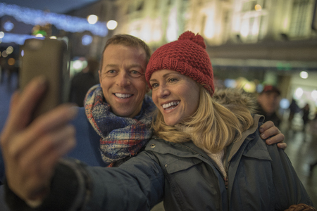 Taking a selfie together in the middle of the city centre, all wrapped up in their warm clothes because of the cold christmassy weather!の写真素材