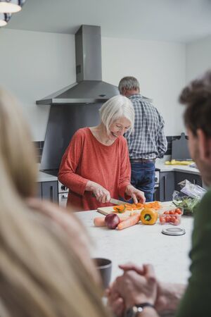 Family are cooking a meal together in the kitchen of the parents' home.  の写真素材
