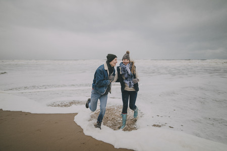 A young couple laugh and paddle in the sea on a winter beach.の写真素材