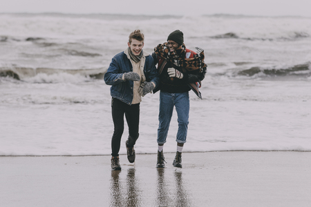 Two friends laughing and having fun on a winter beach.の写真素材