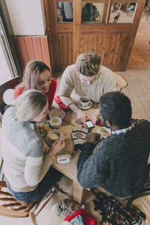 A group of teenagers sitting in a circle enjoying coffee and chatting in winter.の写真素材