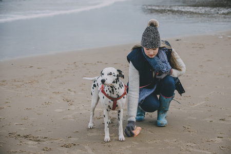Woman cleaning up after dog on a beach in winter.の写真素材