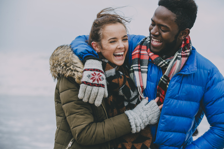 A young couple with arms around each other laughing and having fun.の写真素材