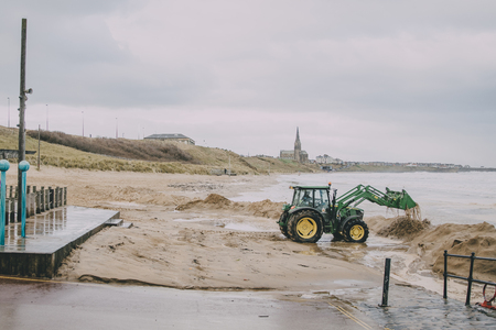 A tractor digs in the sand on Tynemouth beach in winter.の写真素材