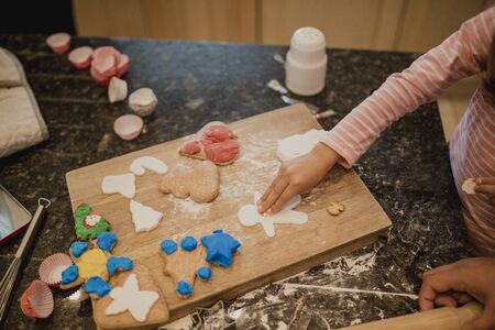 Clsoe up shot of a little girl making christmas biscuits with icing in the kitchen of her home.の写真素材