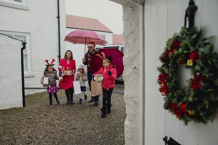 Cheerful family are walking to grandmas house for christmas. They are wearning christmas decorations...