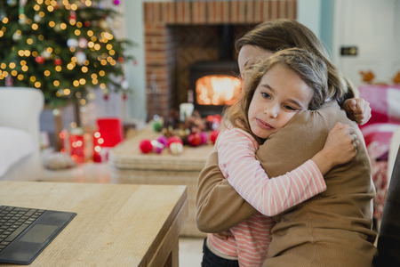 Sad little girl is cuddling with her mother at christmas time.の写真素材