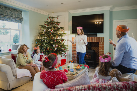 Family are playing charades at christmas time in the living room of their home. It's the mother's turn and everyone is trying to guess.の写真素材