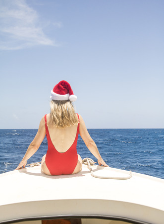Senior woman sits on the front of a boat and enjoys the Caribbean sun at Christmas.の写真素材