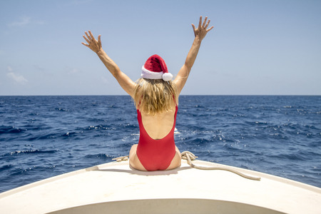A woman sits on the front of a boat and enjoys the winter sun at Christmas.の写真素材