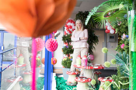 Proud, senior businesswoman posing in the window of her shop.の写真素材