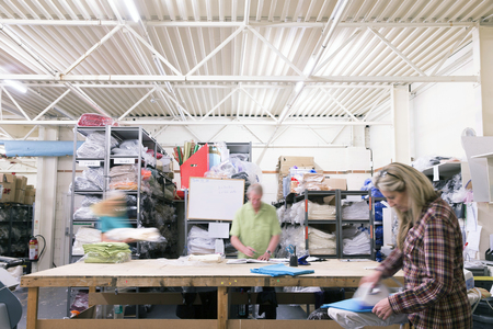 Busy workers in a textile factory. They are pressing and sorting fabric and material.の写真素材