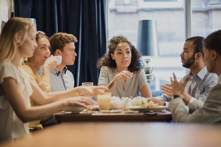 Group of coworkers are having a meeting while enjoying breakfast in a restaurant. の写真素材