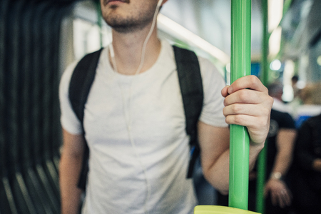Close up shot of a millennial man holding a pole while travelling on a tram in Melbourne, Victoria. の写真素材