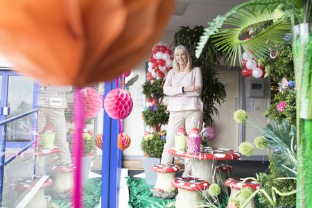 Proud, senior businesswoman posing in the window of her shop. の写真素材