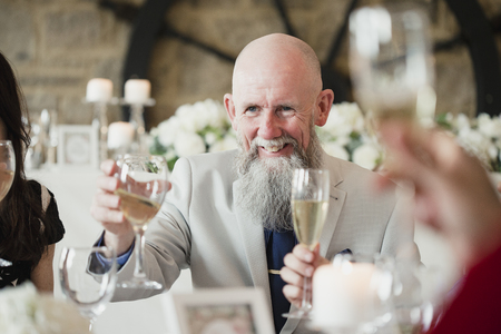 Senior man is raising his glass to a toast at his daughters wedding meal. の写真素材