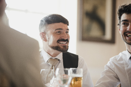 Close up shot of a best man at a wedding, socialising with the guests at the reception. の写真素材
