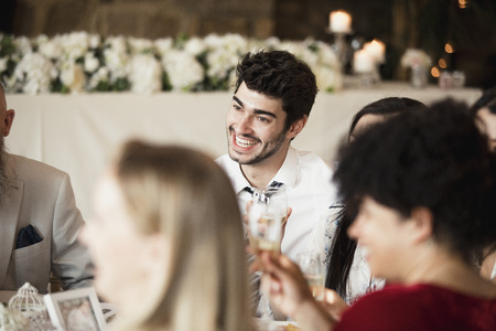 A table of happy wedding guests are socialising as they wait for the starters of their meal. の写真素材