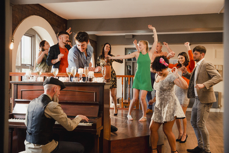 Wedding guests are enjoying a dance while the father of the bride plays piano music. の写真素材