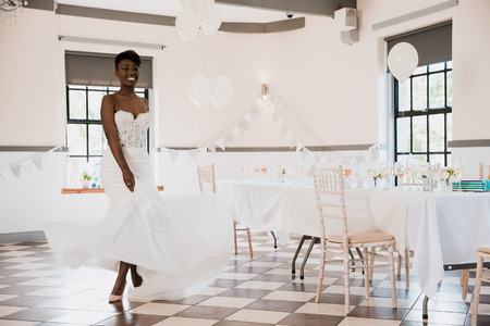 Beautiful bride is dancing on her wedding day. She is mid-twirl and the skirt of her dress is fanning around her legs.の写真素材