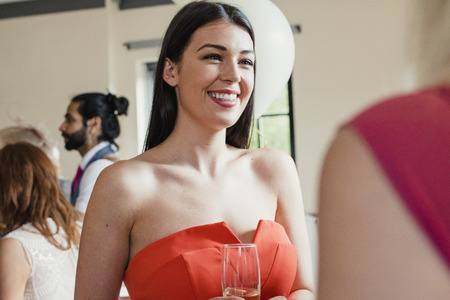Close up shot of a beautiful woman who is socialising at a wedding. の写真素材
