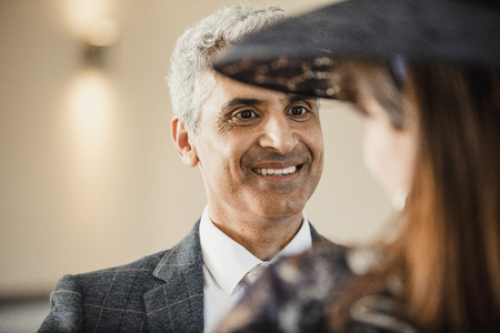 Mature man is having a conversation with his wife at their son's wedding. She has her back to the camera and is wearing a fascinator.の写真素材