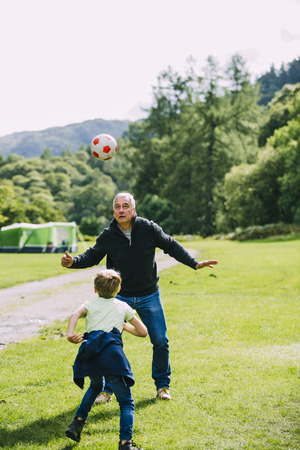 Little boy is playing football with his grandad in the campsite they are staying in. の写真素材