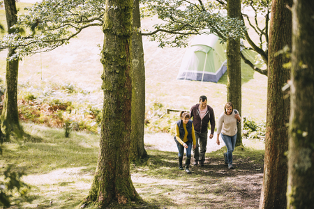 Three mature adults are leaving the campsite to go for a hike together. の写真素材