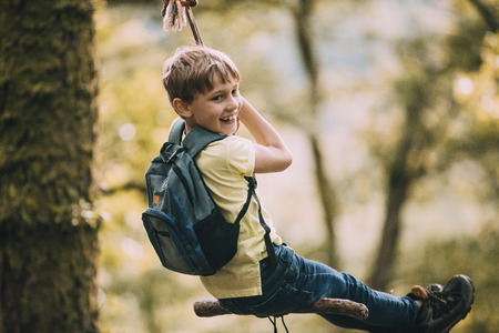 Little boy is having fun on a rope swing which he has found while hiking.の写真素材