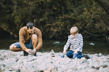 Little boy and his father are building cairns on the beach.の写真素材