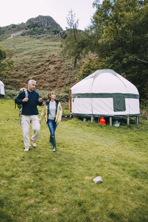 Senior couple are leaving the yurt they have been camping in to go for a hike around the Lake District.の写真素材