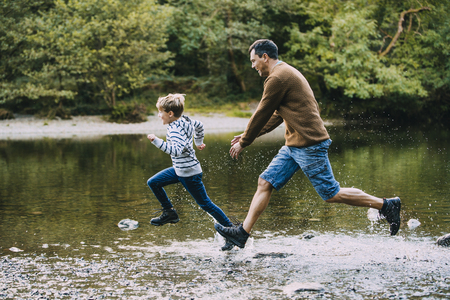 Little boy is being chased in to the lake by his father while they are out hiking. の写真素材
