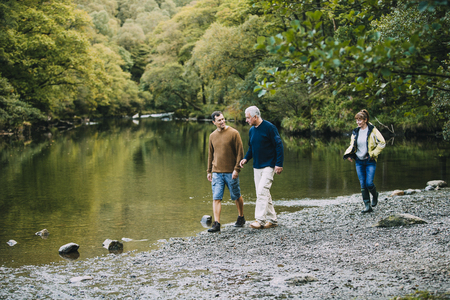 Mid adult man is enjoying a walk around the Lake District with his parents. He is walking with his father and his mother is just behind them.の写真素材