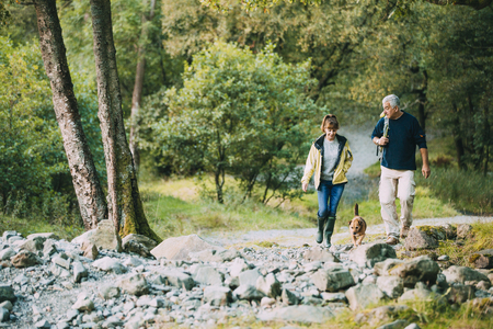 Senior couple are hiking through the Lake District together with their pet dog.の写真素材