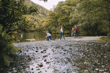 Family are skimming stones on a lake in the Lake District.の写真素材