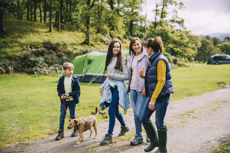 Family are leaving the campsite they are staying in to go for a hike with the dog.の写真素材