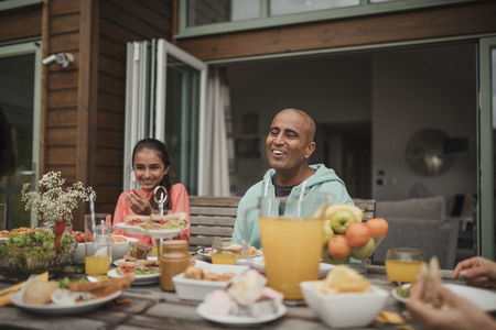 Father and daughter laughing at table during breakfast at a holiday lodge.の写真素材