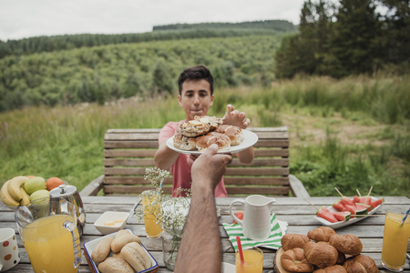 Point of view angle of mixed race boy getting handed a plate of hot cross buns.の写真素材