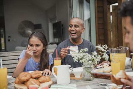 Father laughing and having a morning coffee outside holiday cottage.の写真素材