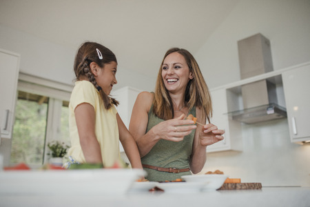 Low angle view of mother and daughter preparing food in the kitchen.の写真素材