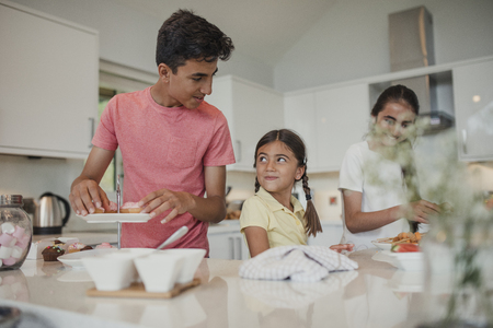 Siblings preparing food in the kitchen.の写真素材