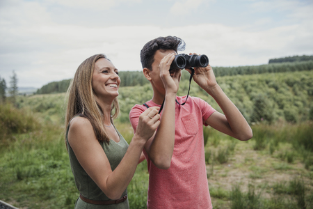 Mother helping son while he looks through the binoculars.